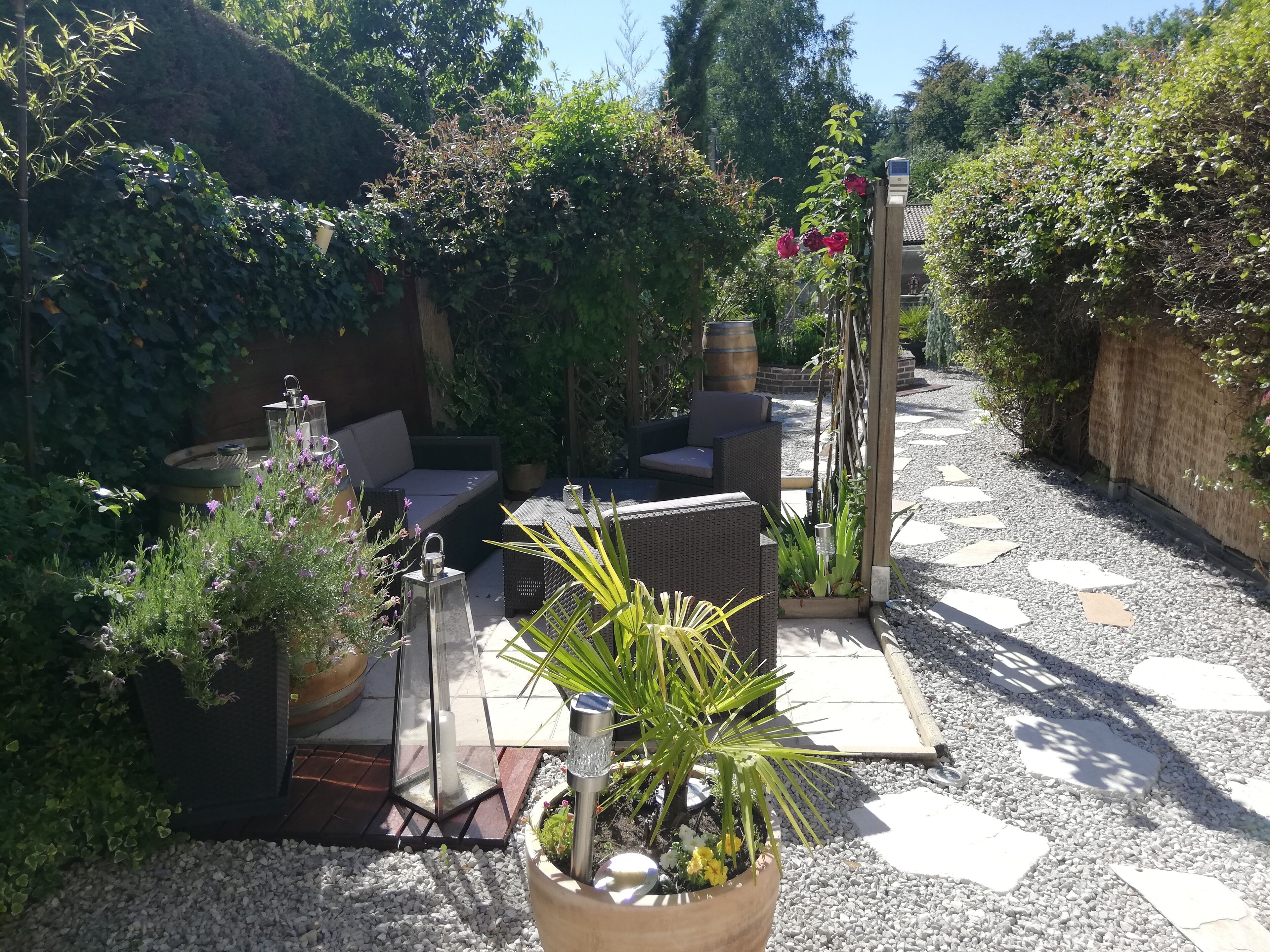 A patio area with outdoor furniture, a water feature, and various plants.