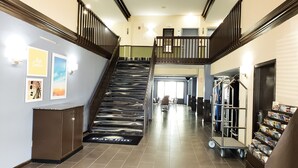 A hotel lobby with a marble staircase, a reception desk, a vending machine, and a bulletin board. - Days Inn & Suites by Wyndham Merrillville (Merrillville)