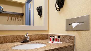 Baño con encimera de granito, lavamanos, espejo, teléfono y dispensador de toallas.