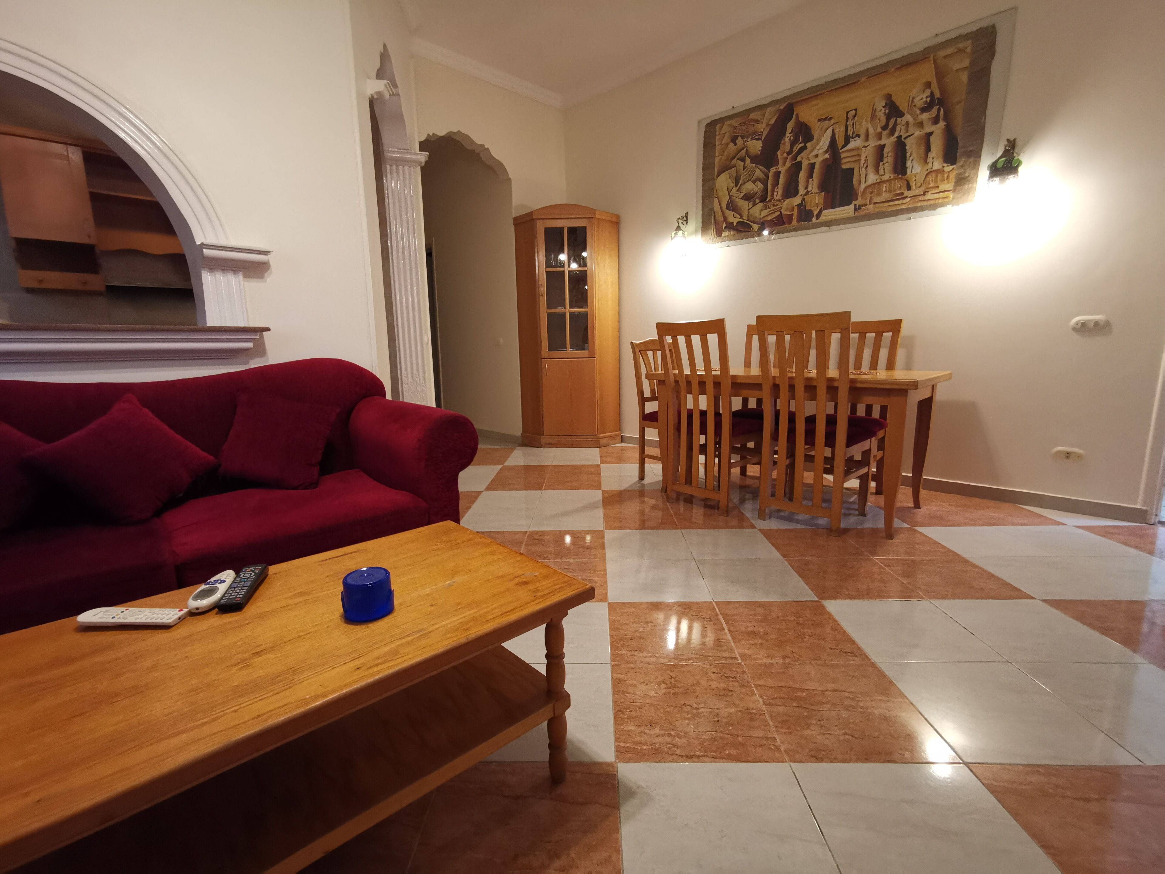 Un salon avec un canapé rouge, une table basse en bois et un coin repas comprenant des chaises et une table en bois.