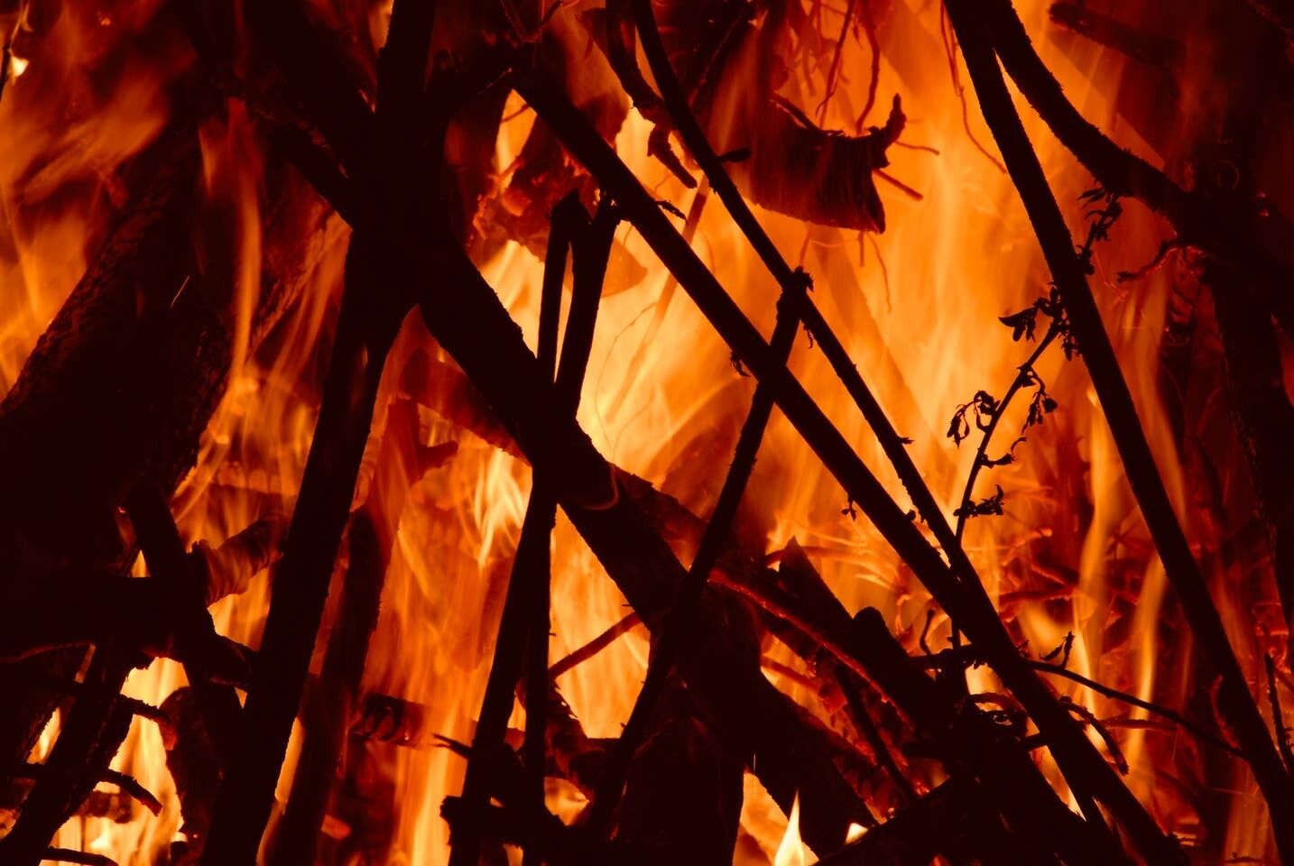 A close-up of a fire with burning branches and logs.