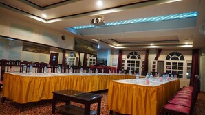 A conference room with long tables covered in yellow tablecloths, equipped with water bottles and nameplates. - Hotel Dewanekhas (Skardu)
