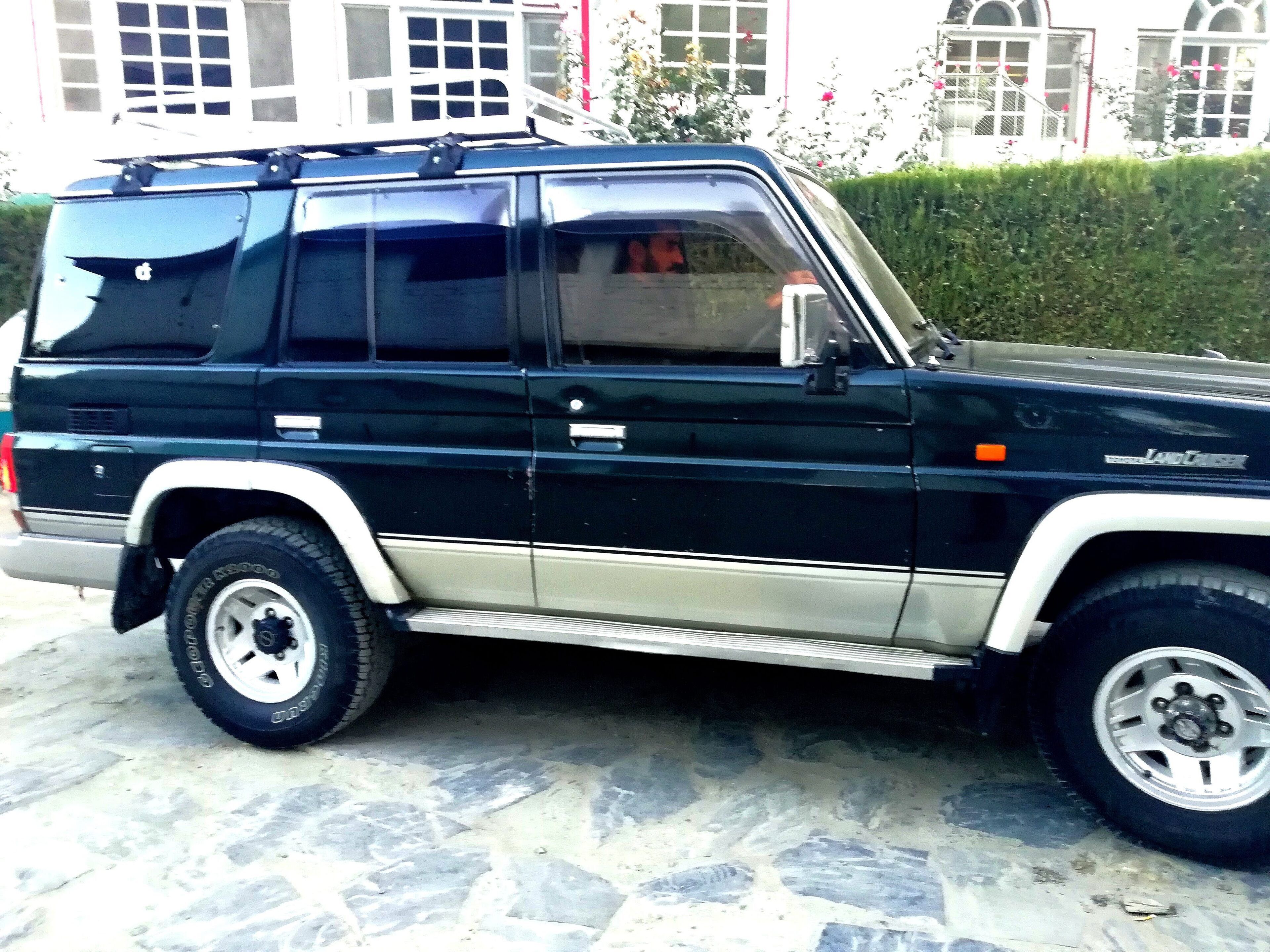 A black and white SUV parked on a stone-paved surface.