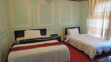 Une chambre d’hôtel avec deux lits, une moquette rouge et une fenêtre avec des rideaux.