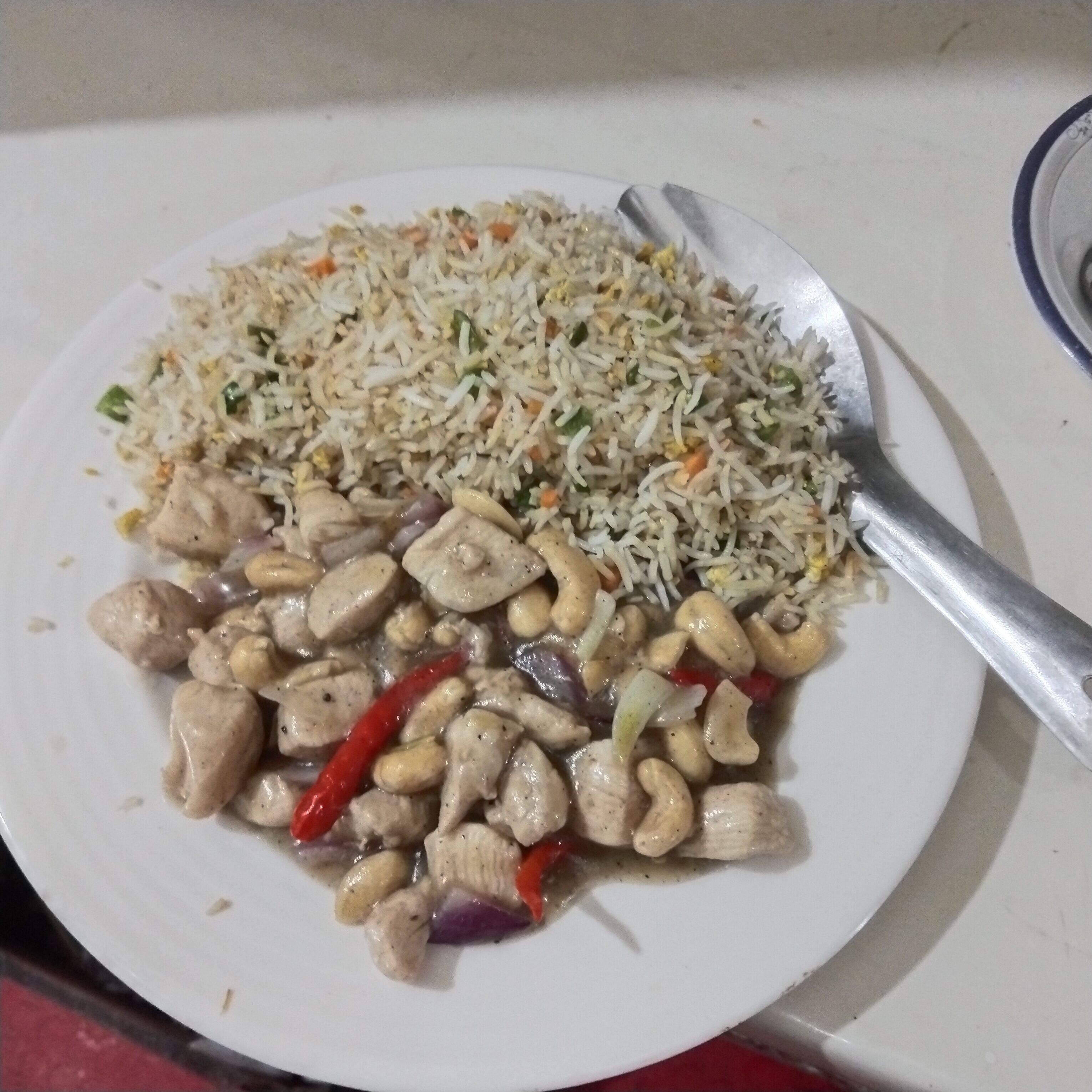 Een bord gebakken rijst met groenten en cashewnoten.