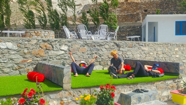 A stone wall with white chairs and a grassy area. - Hotel Dewanekhas (Skardu)