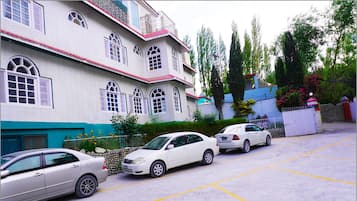 A parking lot with three cars parked in front of a building with multiple windows and a red roof.