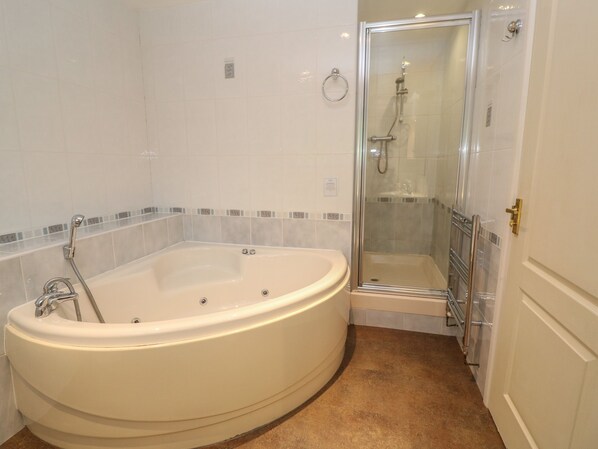 A bathroom with a large freestanding bathtub, a glass-enclosed shower, and a white door.