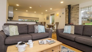 A modern living room with two grey sofas, a wooden coffee table, and a dining area in the background. - Juniper (Truro)