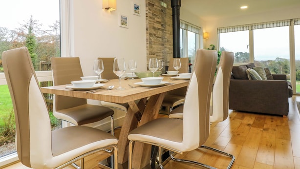 A dining area with a wooden table set for six, surrounded by modern chairs. - Juniper (Truro)