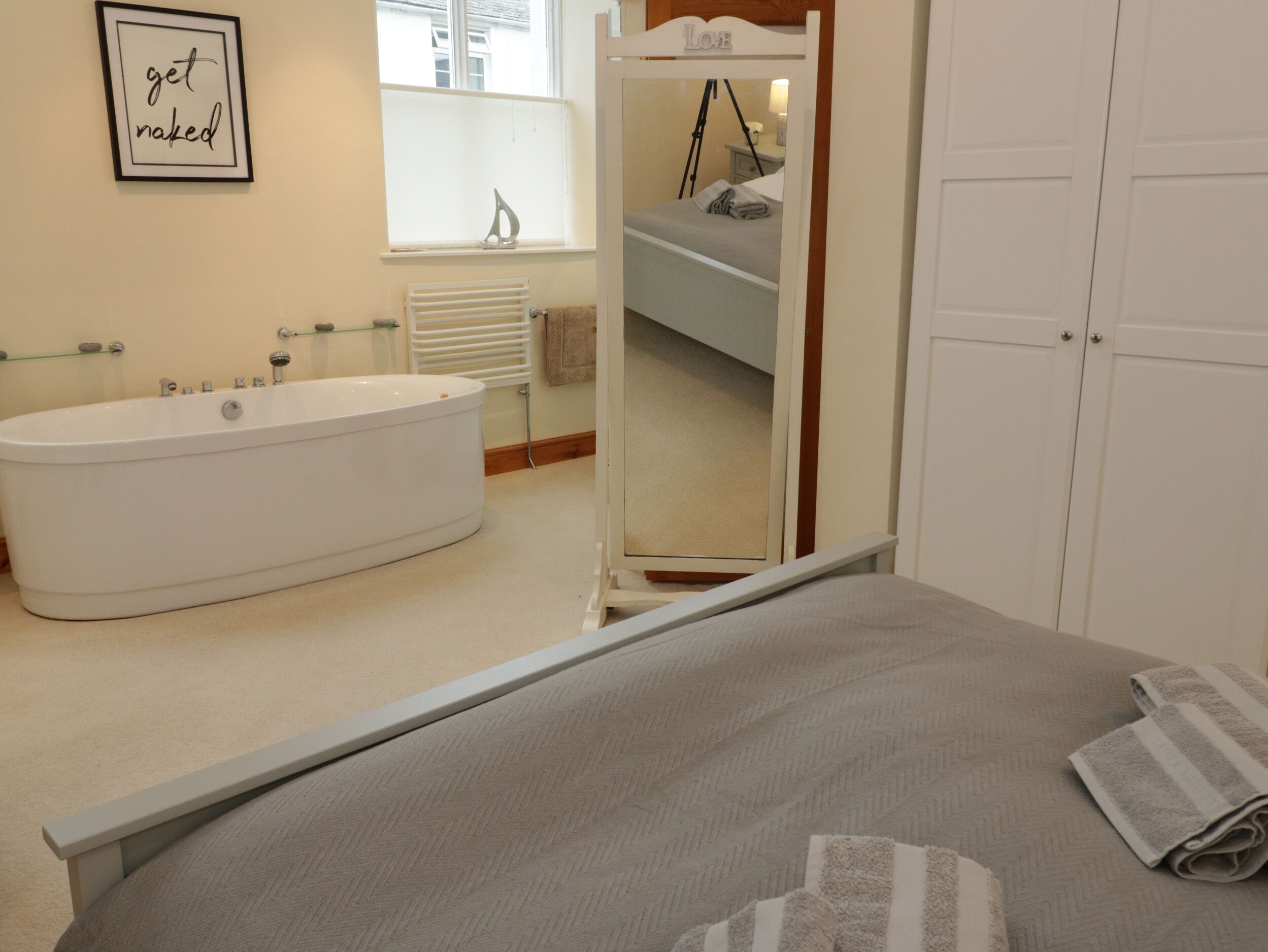 Un dormitorio con una cama grande, una bañera, un espejo y una puerta.