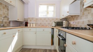 A compact kitchen with white cabinets, a microwave, a gas stove, and a sink.