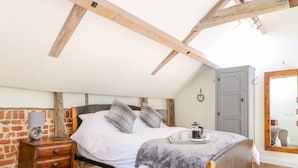 A bedroom with a bed, wooden dresser, and a wardrobe. - The Cart Shed (Dereham)