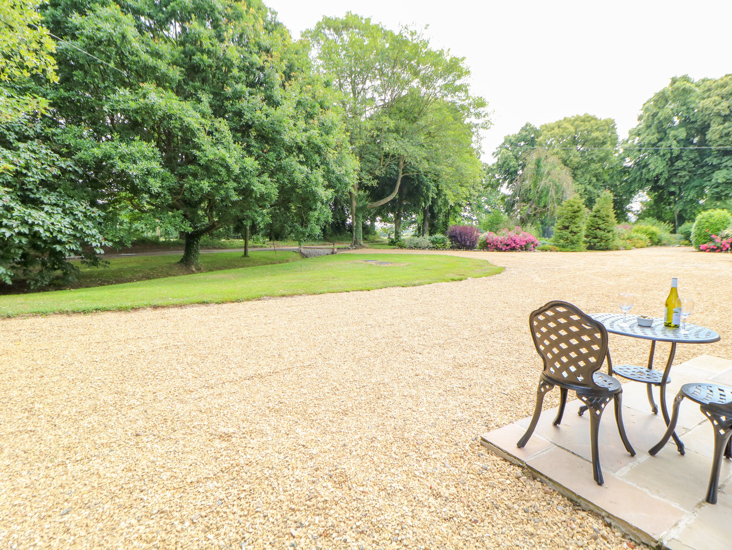 A gravel patio with outdoor seating and a view of a lush garden.