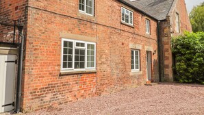 A traditional brick building with multiple windows and a gravel driveway. - Well House Farm Flat 1 (Chester)