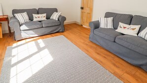 A living room with two grey sofas, patterned rugs, and a wooden door. - Well House Farm Flat 1 (Chester)