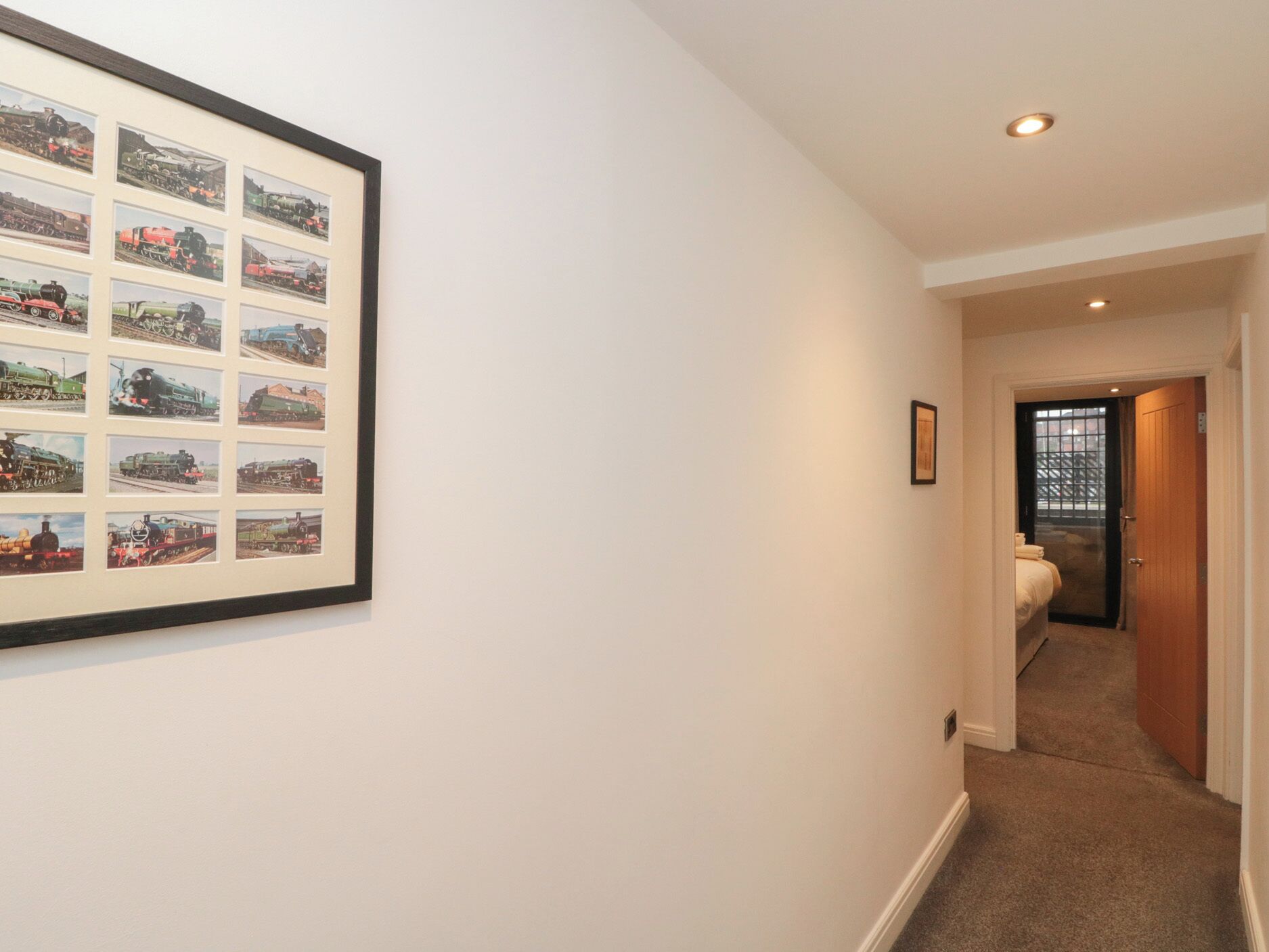 A hallway with a framed collection of vintage train photographs on the wall.