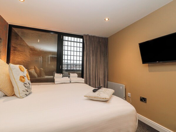 A modern hotel room with a large bed, a flat-screen TV mounted on the wall, and a large window with curtains. - Sir Nigel Gresley @ Engine Shed (Whitby)