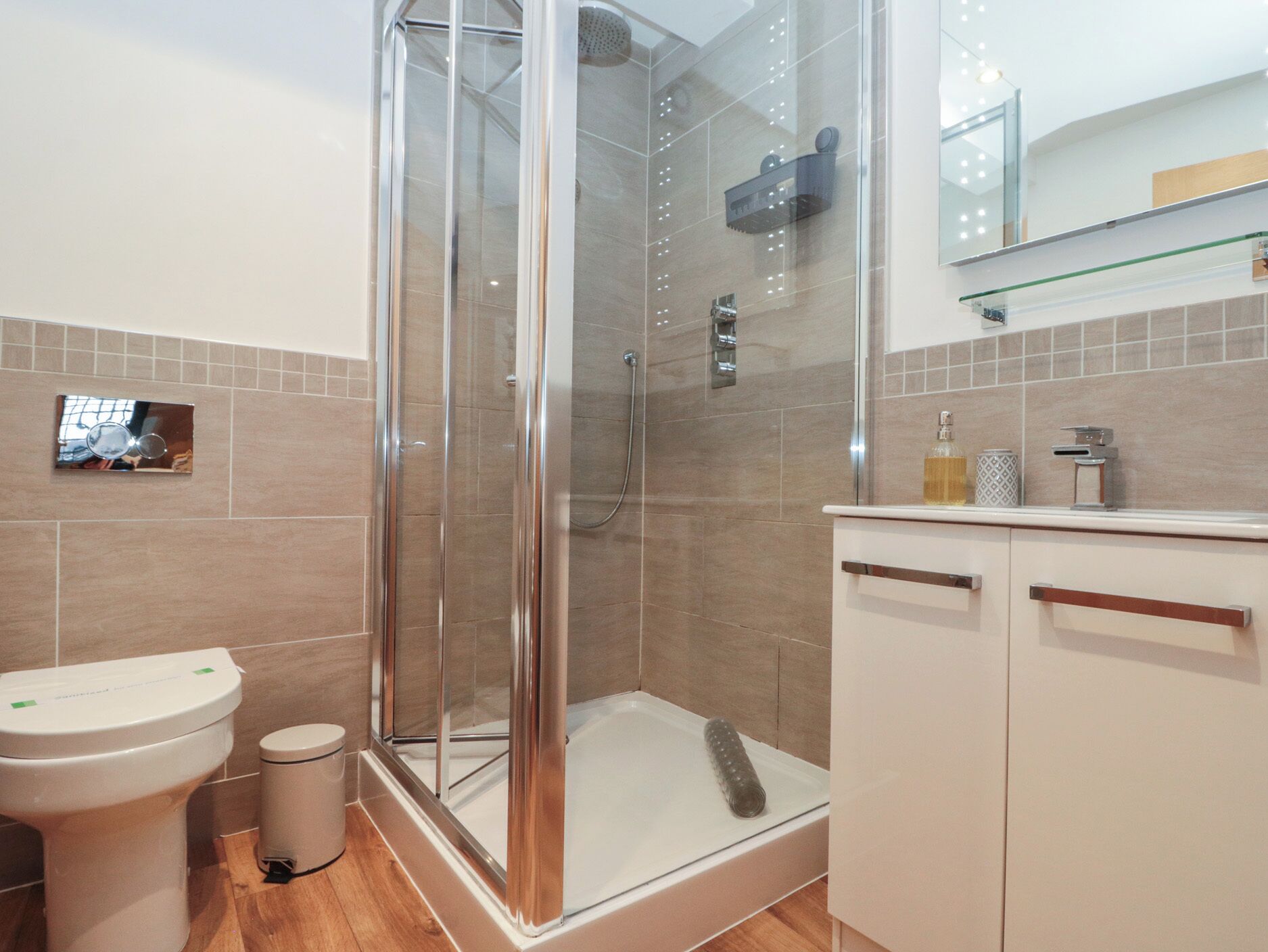 Et moderne badeværelse med en glasafskærmet brusekabine, toilet og vask.
