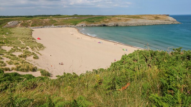 A beach with a clear view of the sea, sandy shore, and grassy dunes. - Shepherds Hut - The Crook (Milford Haven)