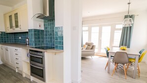 A modern kitchen with white cabinets, a built-in oven, and teal backsplash tiles. - Senafe (Bude)