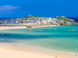 Un pueblo costero con playa, aguas cristalinas y edificios históricos.