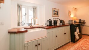 Une cuisine équipée d’un évier encastré, de meubles en bois, d’une cuisinière et d’une fenêtre avec des rideaux.