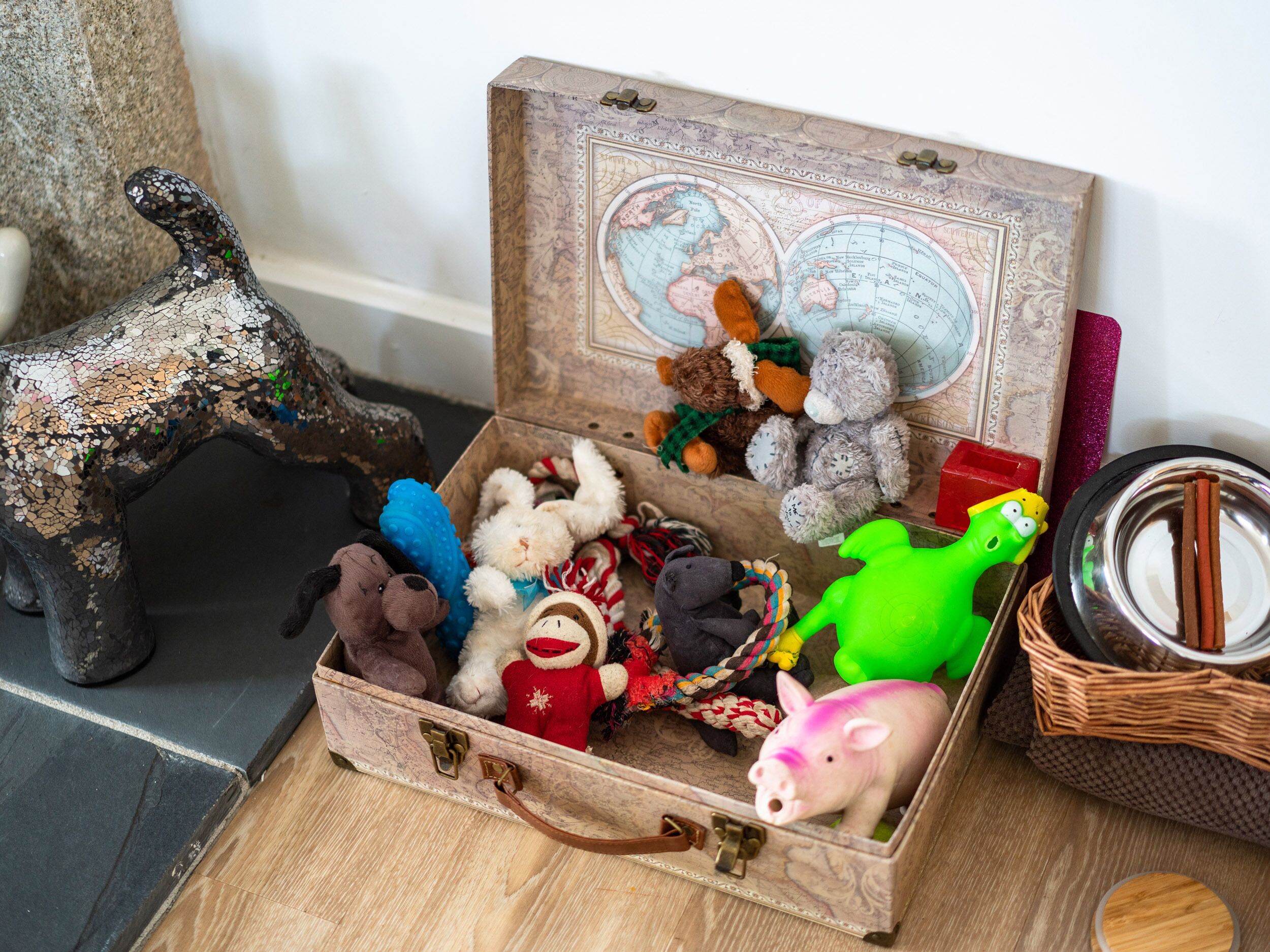 Une vieille valise remplie de peluches et d’un globe terrestre.