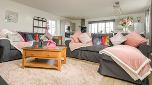 A modern living room with two sofas, a wooden coffee table, and a fluffy rug. - Be Our Guest Cottage (Truro)