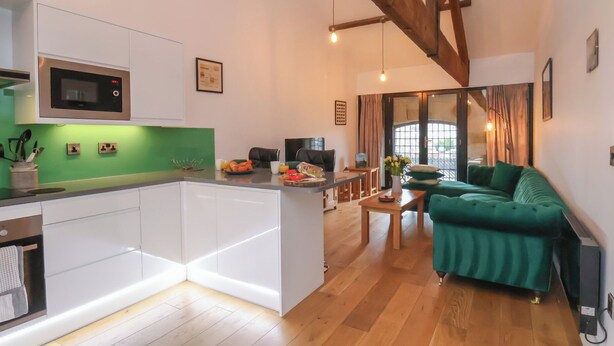 A modern kitchen with white cabinets, a green backsplash, and a built-in microwave. - Repton @ Engine Shed (Whitby)