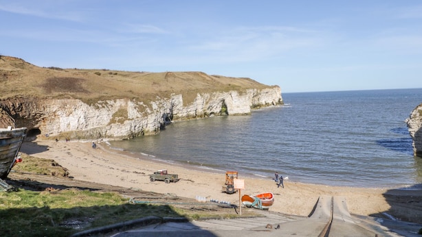 A coastal landscape with cliffs, a sandy beach, and a clear sky. - Gough Bank (Bridlington)