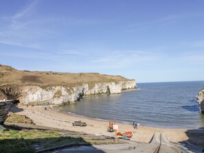 Eine Küstenlandschaft mit Klippen, einem Sandstrand und wolkenlosem Himmel.