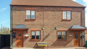 A two-story brick building with a tiled roof, two windows on the ground floor, and a bench in front. - Gough Bank (Bridlington)
