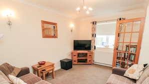 A living room with two sofas, a TV stand, a small table, and a bookshelf. - Gough Bank (Bridlington)