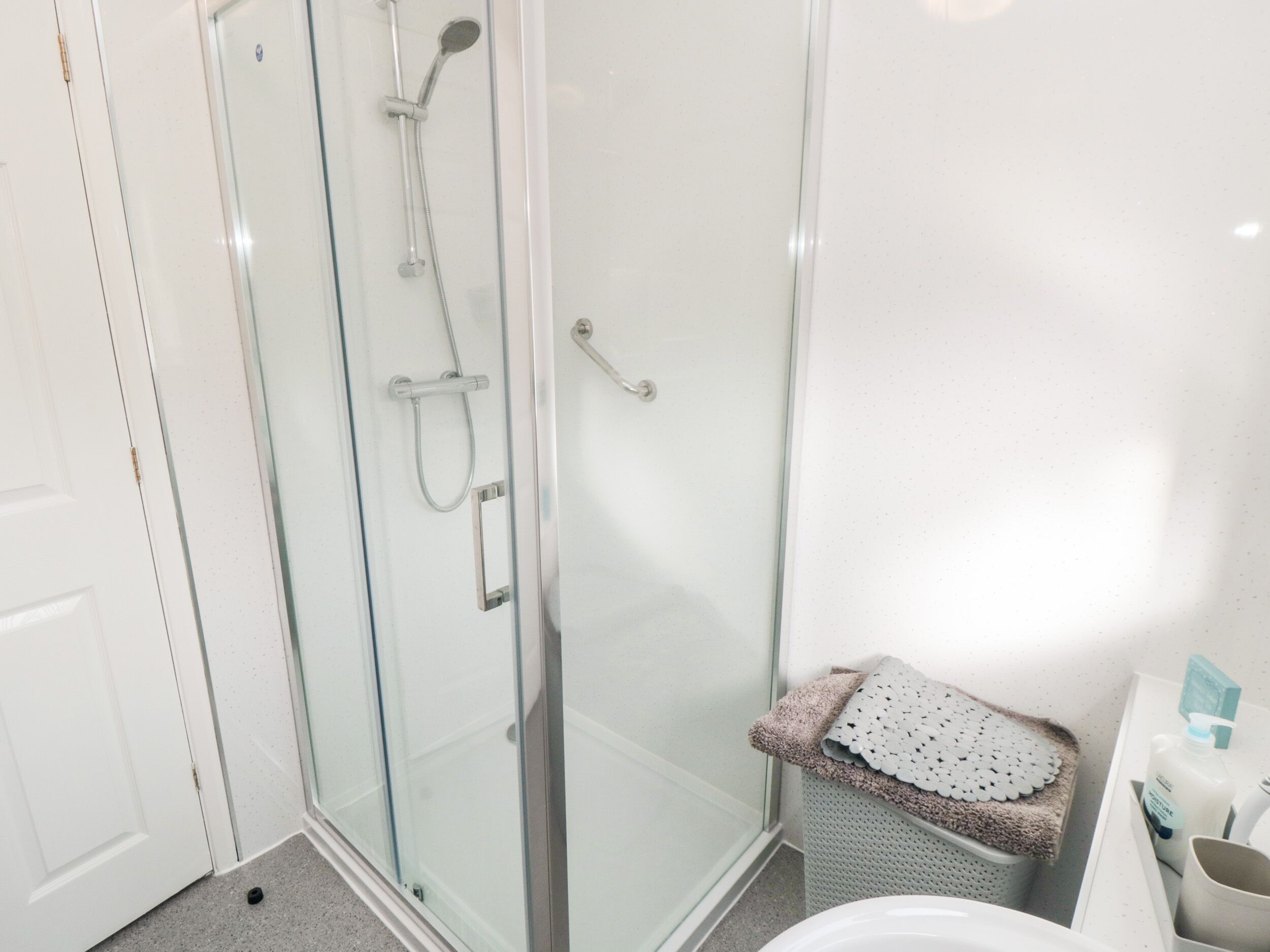 Un baño con ducha de vidrio, inodoro y lavabo con toalla y artículos de aseo.