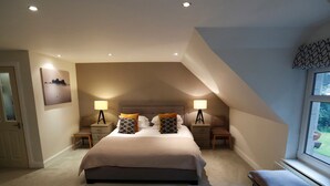 A bedroom with a large bed, two bedside tables with lamps, a chair, and a window.