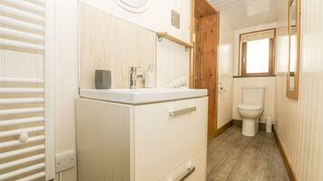 A compact bathroom with a white sink, wooden door, and a toilet.