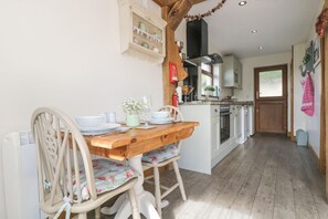 A cozy kitchen with wooden furniture, a dining table, and a view into the adjacent dining area. - The Lily Pad (Camborne)