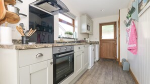 A kitchen with white cabinets, a built-in oven, a microwave, and a wooden countertop. - The Lily Pad (Camborne)