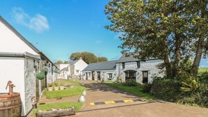 A village street with stone buildings, a paved path, and greenery. - Cowslip Cottage (Milford Haven)