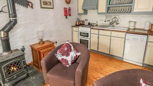 A cozy kitchen with a stove, wooden cabinets, and a sink. - Cowslip Cottage (Milford Haven)