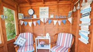 Une cabane en bois chaleureuse, avec deux chaises à rayures, une horloge et un panneau décoré de motifs marins.