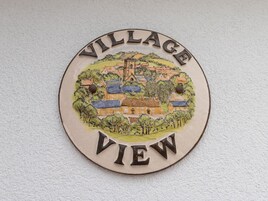 Un letrero circular con una escena de un pueblo y la inscripción 'VILLAGE VIEW'.