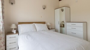 A bedroom with a bed, bedside tables, a wardrobe, and a mirror. - Village View (Bridport)