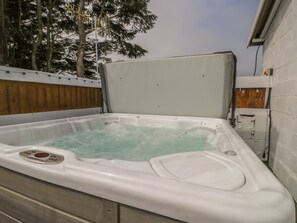 A hot tub with a control panel, surrounded by a wooden fence and trees. - The Sequoia (Scarborough)