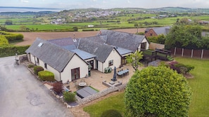 A large house with a spacious patio, a fenced yard, and a view of the surrounding countryside.