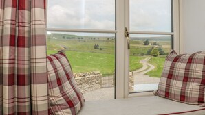 A room with a large window, a view of a green landscape, and a stone wall. - The Aspens (Barnard Castle)