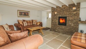 A cozy living room with a stone fireplace, a sofa set, and a coffee table. - The Aspens (Barnard Castle)