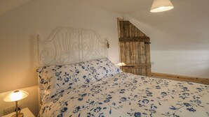 A bedroom with a bed, a wooden door, a white headboard, and a bedside lamp. - 11 Village (Banff)