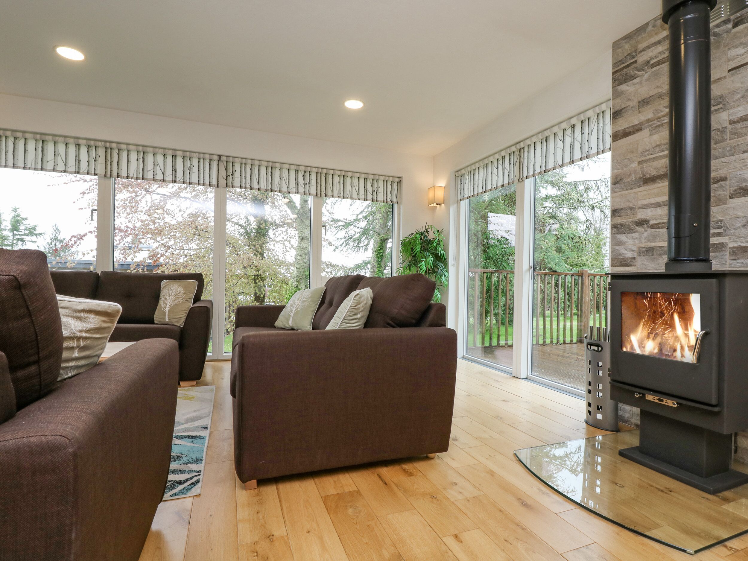 A modern living room with a fireplace, large windows, and a balcony.